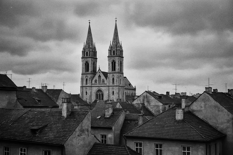Dvě věže katedrály nad střechami města proti zatažené obloze